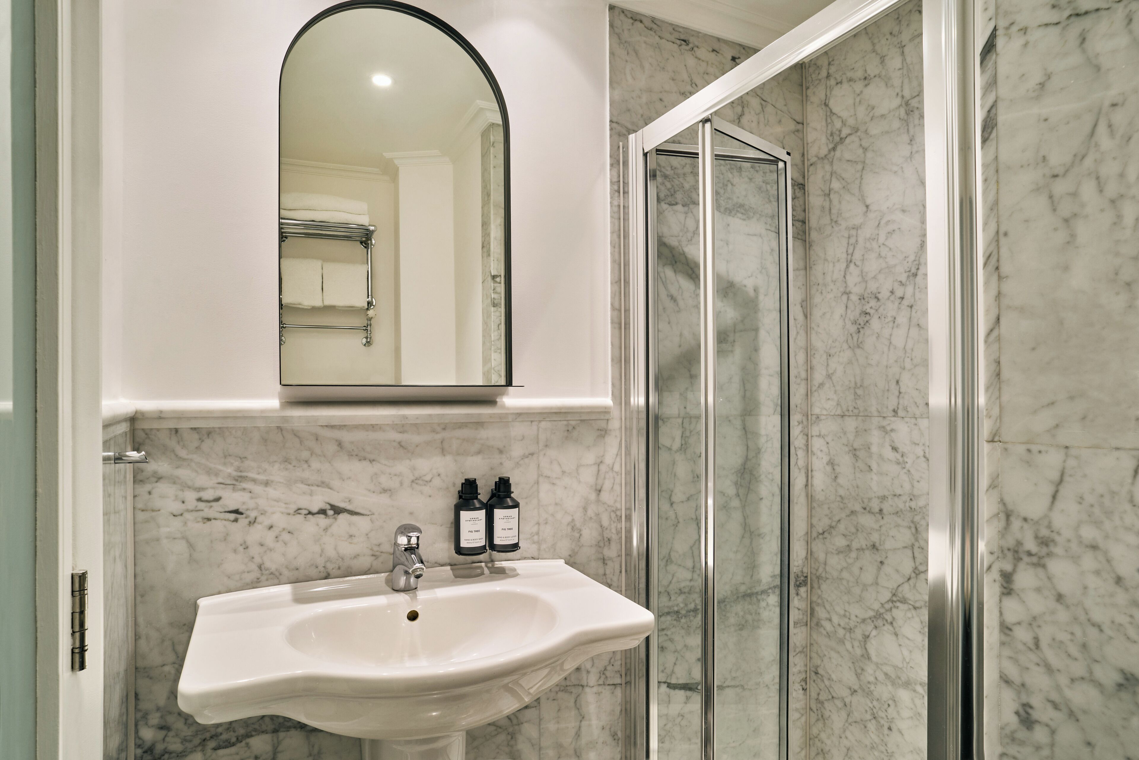 A bathroom with a white sink, a mirror, and a shower area.