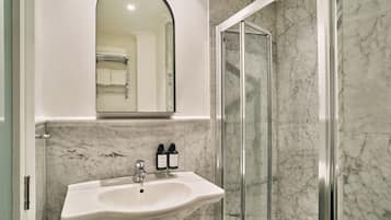 A bathroom with a white sink, a mirror, and a shower area.