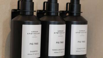 Three black bottles of Urban Apothecary Fig Tree products on a tiled wall.