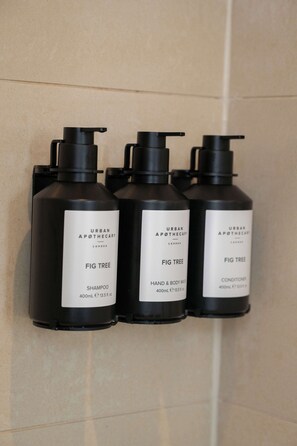 Three black bottles of Urban Apothecary Fig Tree products on a tiled wall.