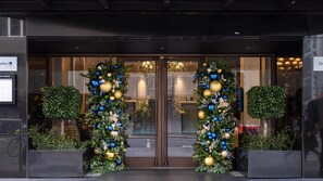 A hotel entrance with a glass door, a Christmas tree, and a sign for Radisson. - Guild Hotel Fitzrovia (London)