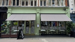 A green building with two striped awnings, a signboard, and a row of tables and chairs outside. - Radisson Blu Hotel, London Euston Square (London)
