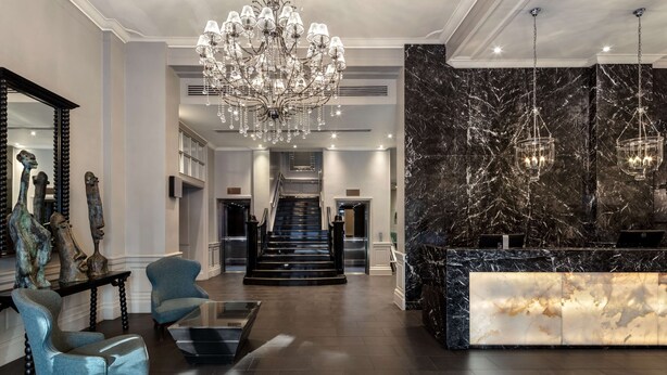 A spacious lobby with a grand chandelier, a marble reception desk, and a staircase leading to upper floors. - Radisson Blu Hotel, London Euston Square (London)