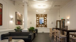 A modern lobby with a sofa, chairs, a coffee table, a large mirror, and a decorative window with a view. - Radisson Blu Hotel, London Euston Square (London)