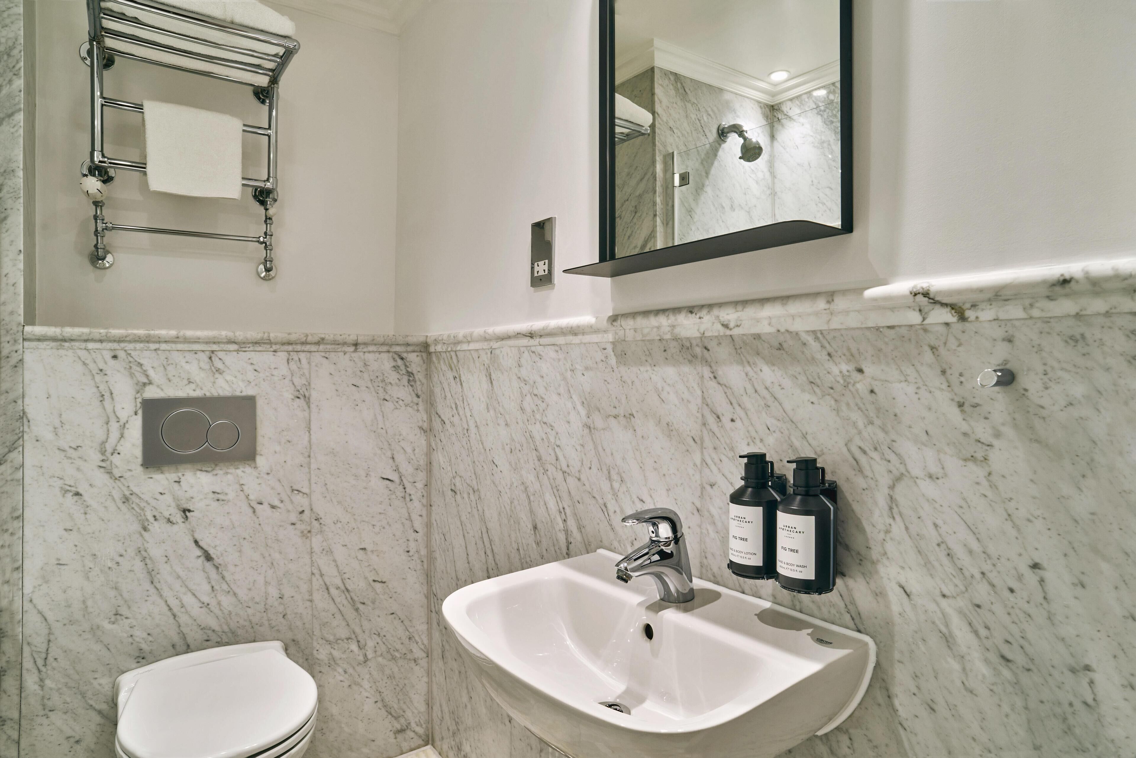 A bathroom with a white sink, a mirror, and a towel rack.