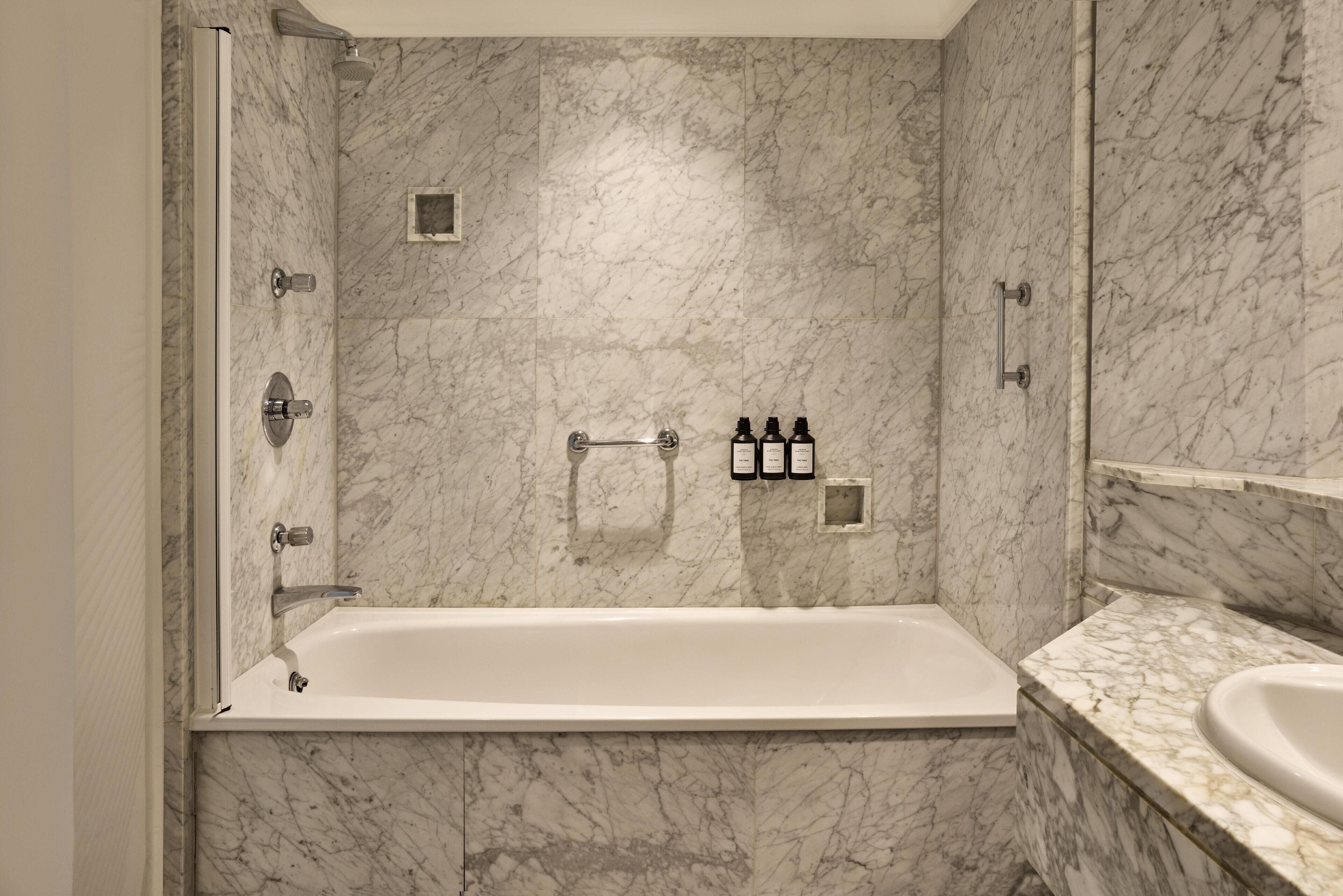 Un baño moderno con pared de mármol, bañera y zona de ducha.