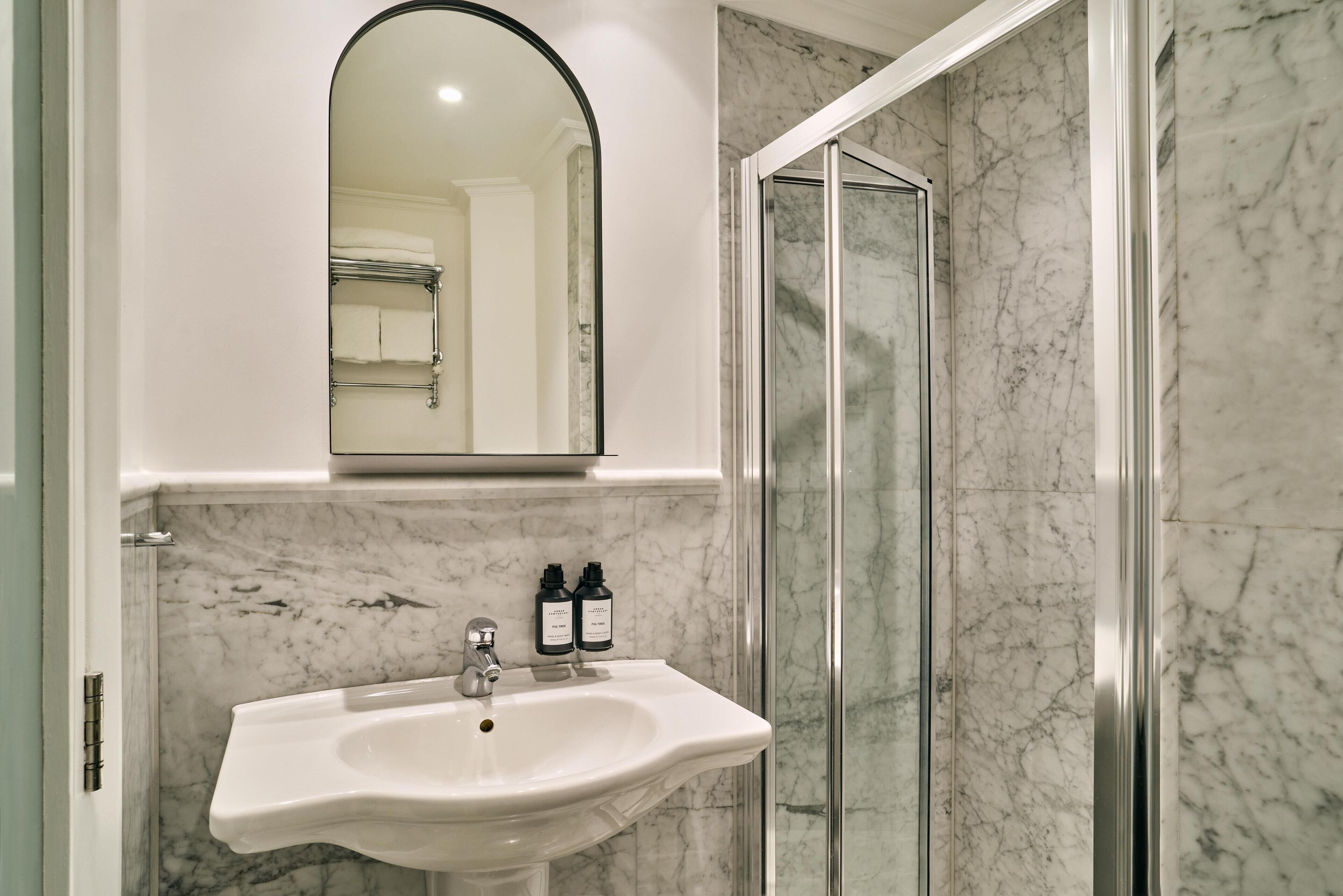 Un baño con lavamanos blanco, un espejo y una ducha.
