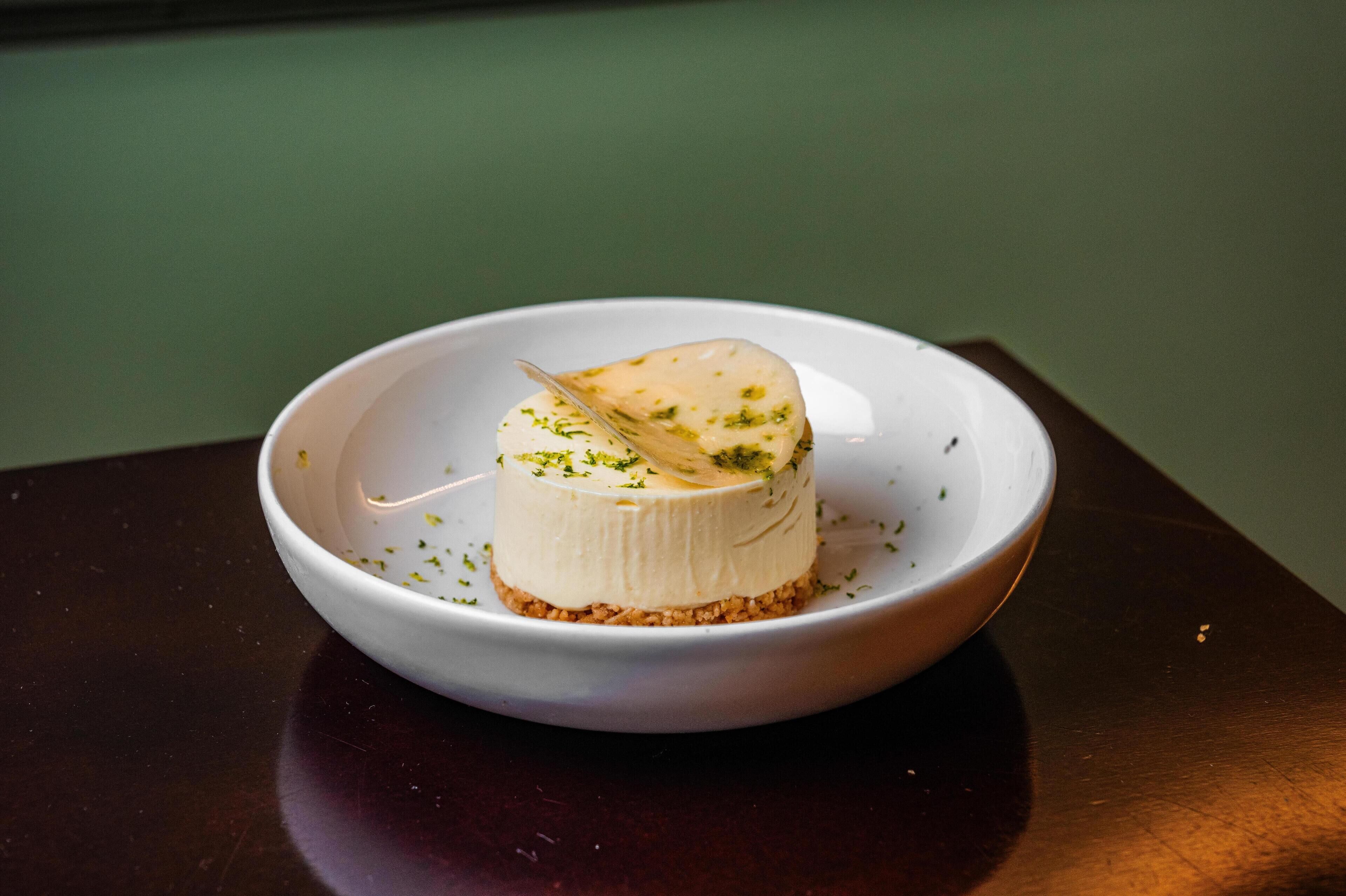 A dessert on a white plate with a green background.