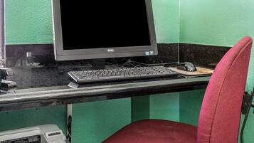 A computer desk with a Dell monitor, keyboard, mouse, and a red chair.