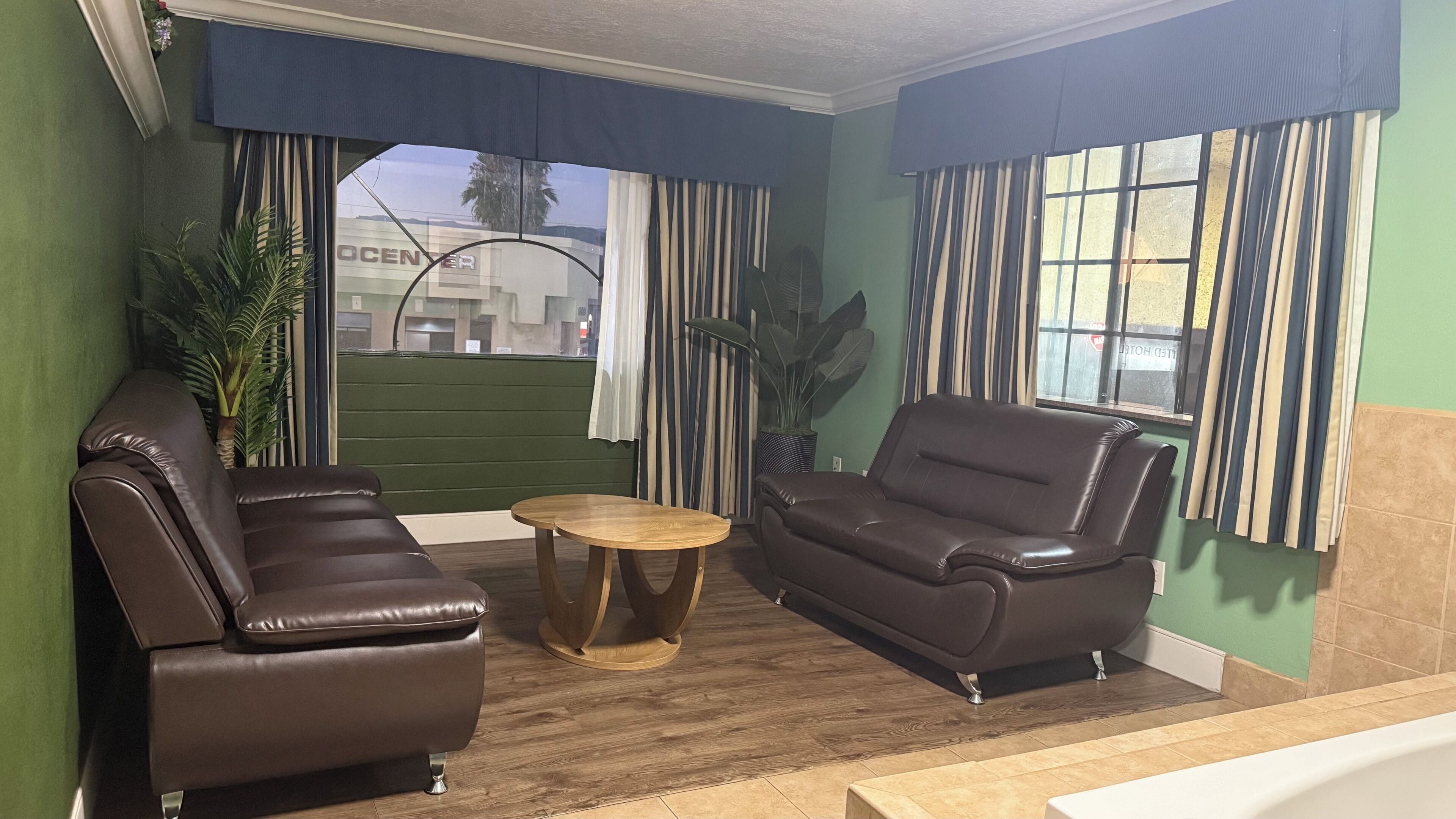 A room with two leather sofas, a wooden coffee table, and a view of the outside.