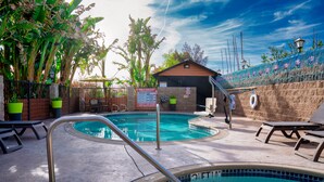 Une piscine dont le bord est revêtu de carrelage, entourée de chaises longues et de plantes en pot.