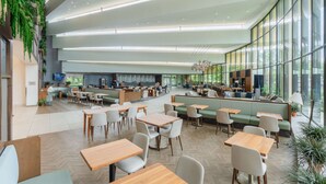 A spacious indoor area with multiple seating options including tables and benches, a counter area, and large windows providing natural light. - Hilton Memphis (Memphis)