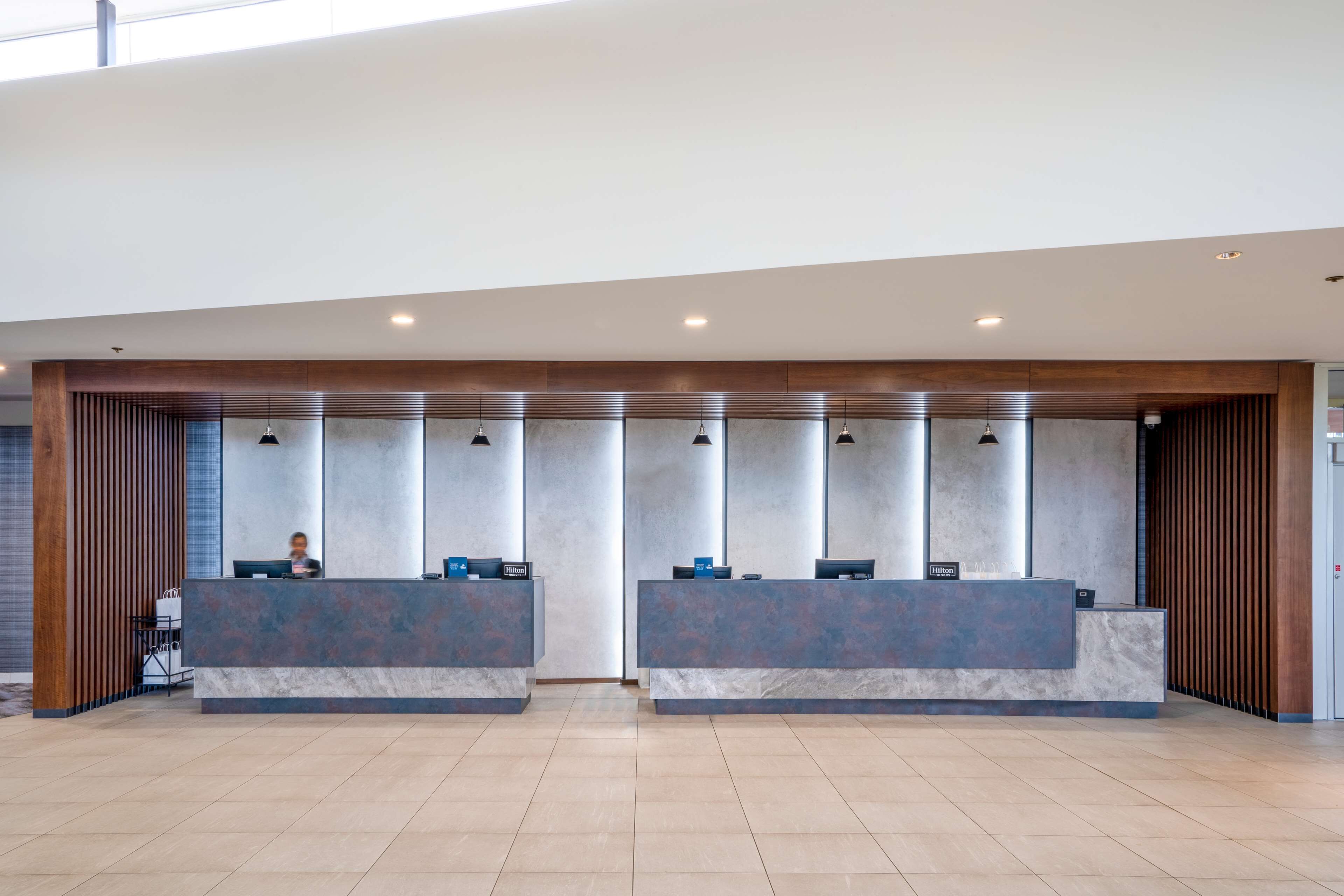A hotel reception area with two reception desks, a receptionist, and a modern interior design.
