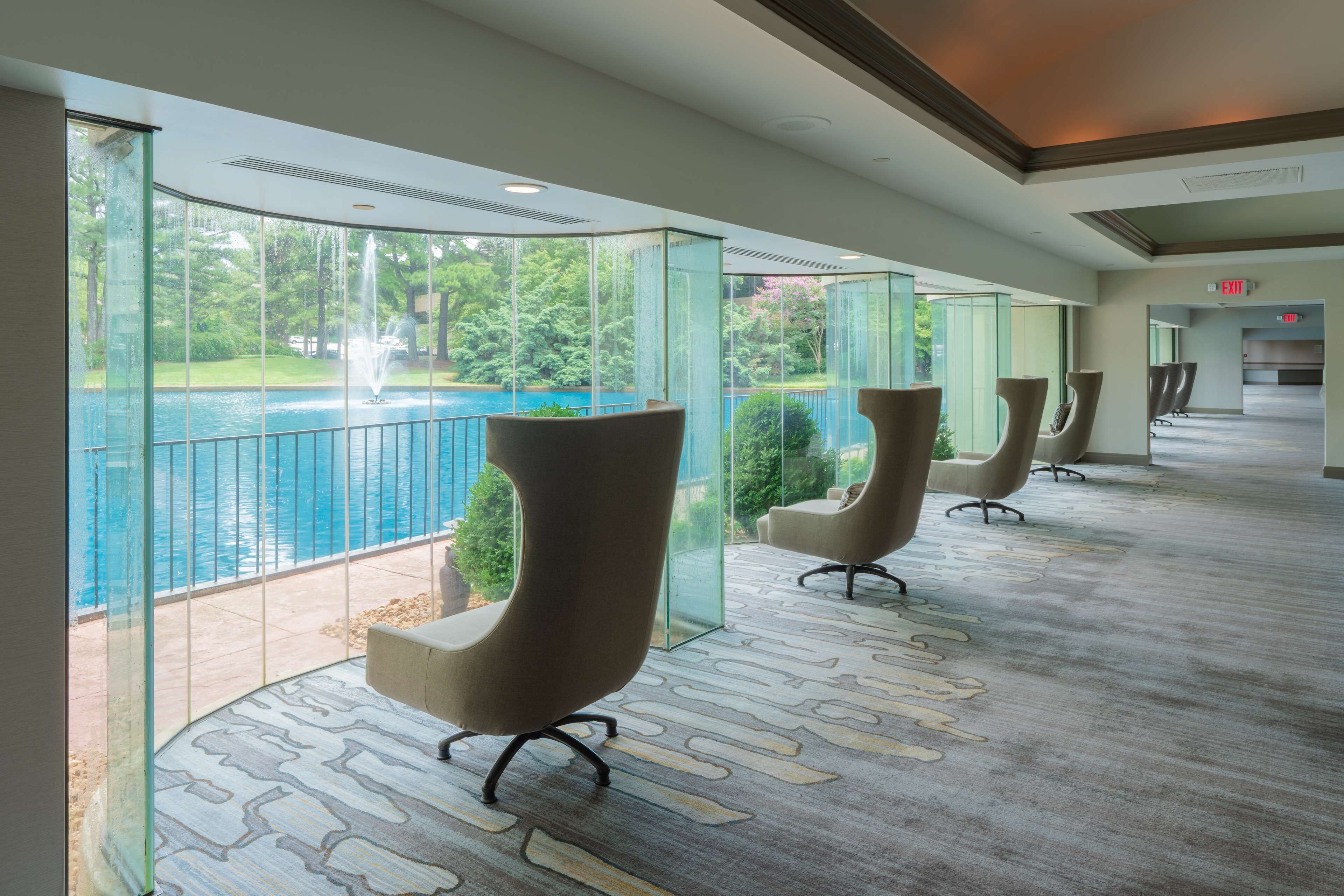 A modern hotel lobby with a pool view, glass walls, and contemporary seating.