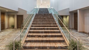 A grand staircase with glass railings leading to a well-lit upper floor. - Hilton Memphis (Memphis)