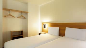 Habitación de hotel con una cama grande, cabecero de madera, mesita de noche y lámpara de pared.