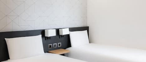 A hotel room with two beds, a wooden nightstand, and a geometric-patterned wall.