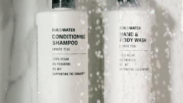 Two bottles of shampoo and body wash with a pump dispenser, both labeled as 100% vegan and supporting the community.