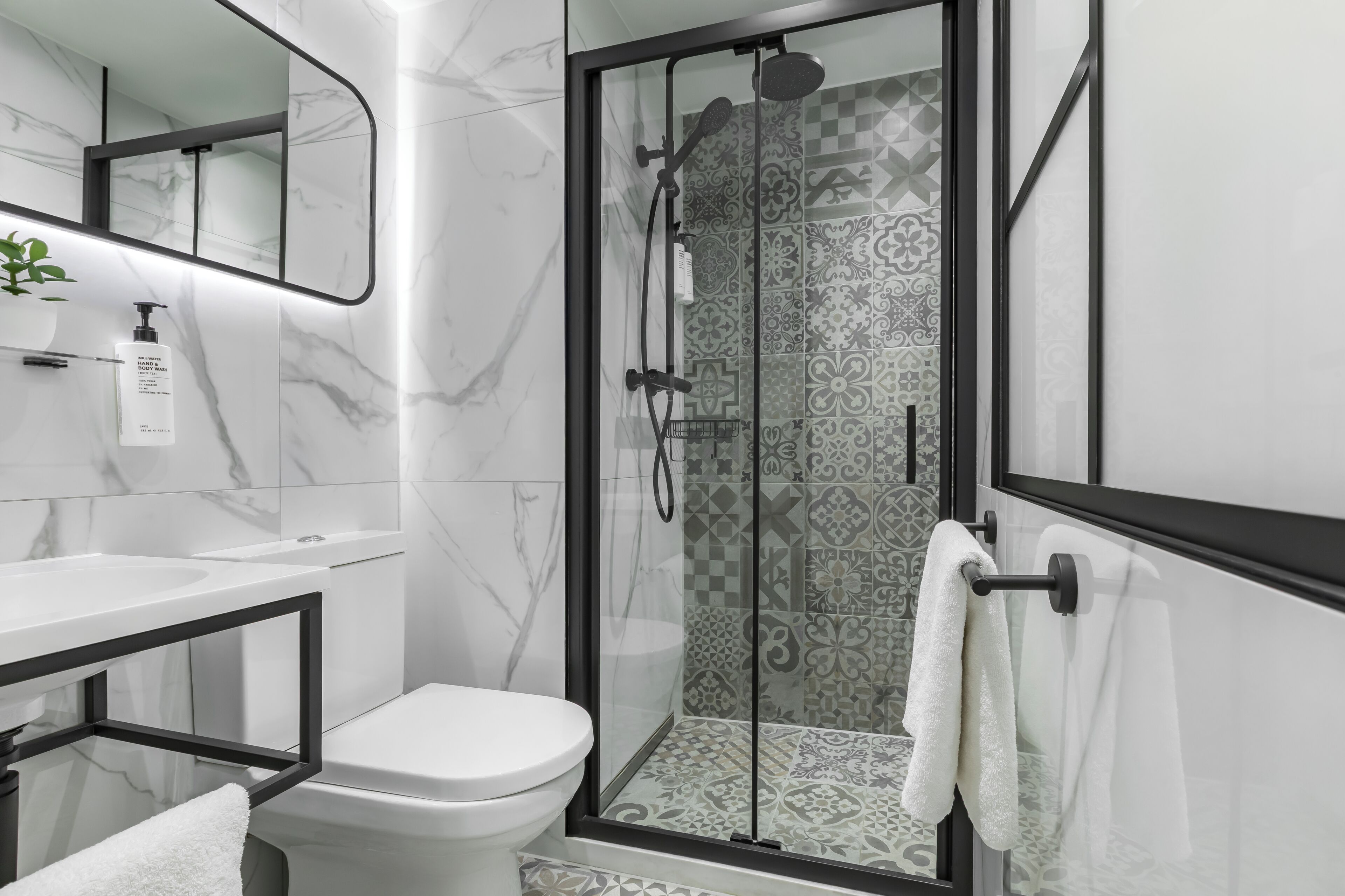 A modern bathroom with a glass-enclosed shower, a white toilet, and a marble sink.