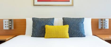 A hotel room with a bed, two nightstands, a wall-mounted light, and a framed picture.
