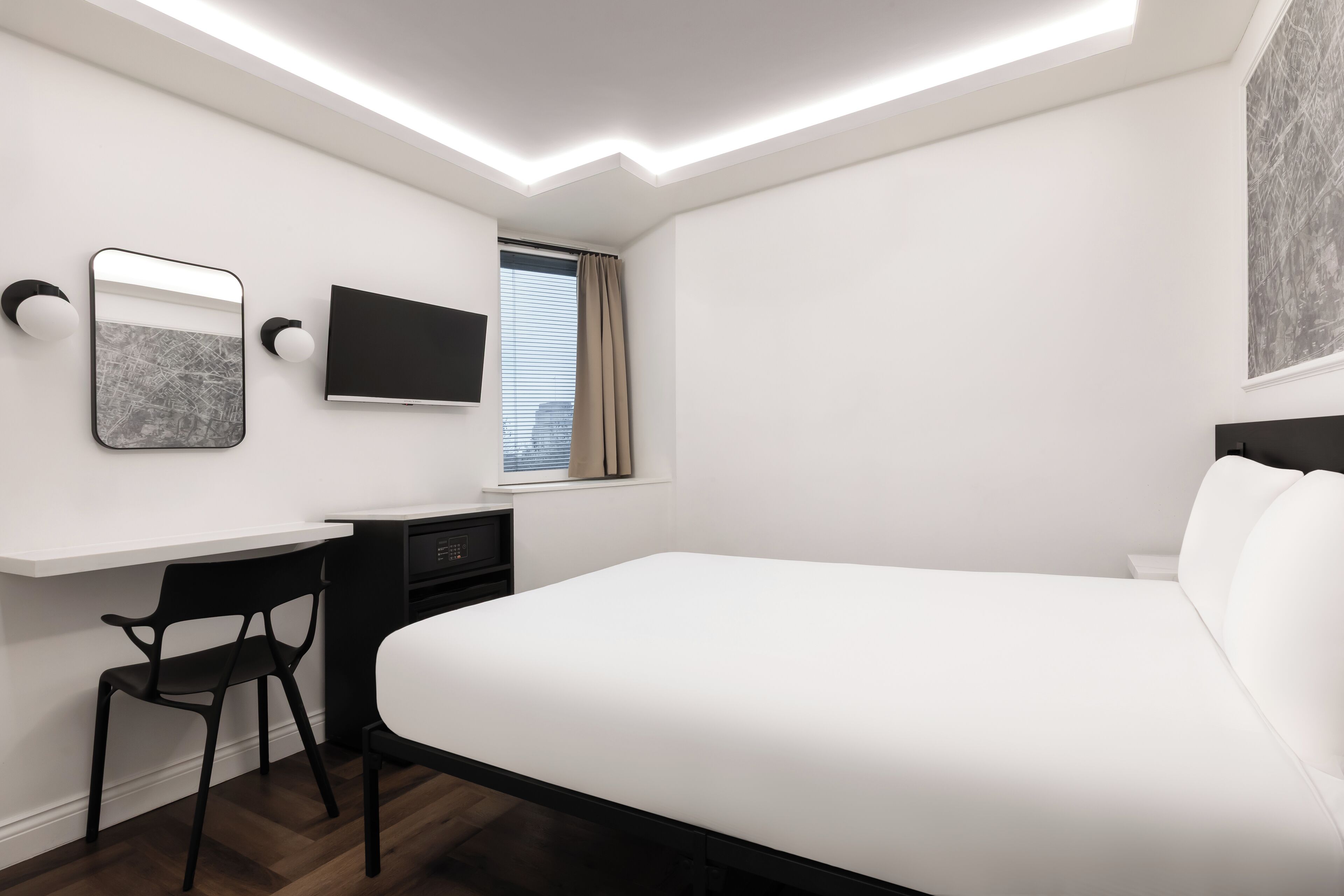 Una habitación de hotel moderna con una cama grande, un escritorio, una silla, un televisor de pantalla plana y una ventana con cortinas.
