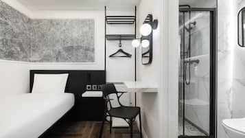 Ein modernes Hotelzimmer mit Bett, Schreibtisch, Stuhl, Dusche und einem großen abstrakten Wandbild.