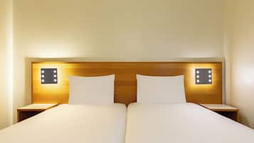 A double bed with white linens, two bedside tables, and wall-mounted light fixtures.