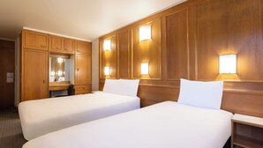A hotel room with two beds, wooden paneling, a desk, and a mirror. -  STG Hotel London Oxford Street (London)