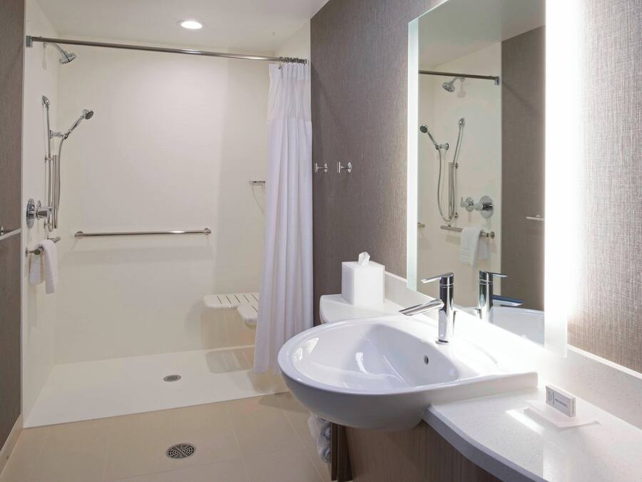 Uma casa de banho moderna com chuveiro envidraçado, lavatório branco e um espelho grande.