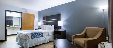 Una habitación de hotel con una cama, mesitas de noche, una silla, una mesa y una lámpara.