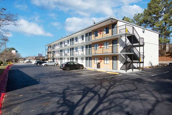 A multi-story motel with a central staircase, a parking lot, and a clear sky.