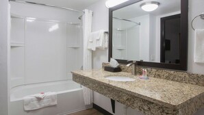 A bathroom with a granite countertop, a sink, a mirror, a shower, and a bathtub. - Econo Lodge Lithonia - Atlanta East (Lithonia)