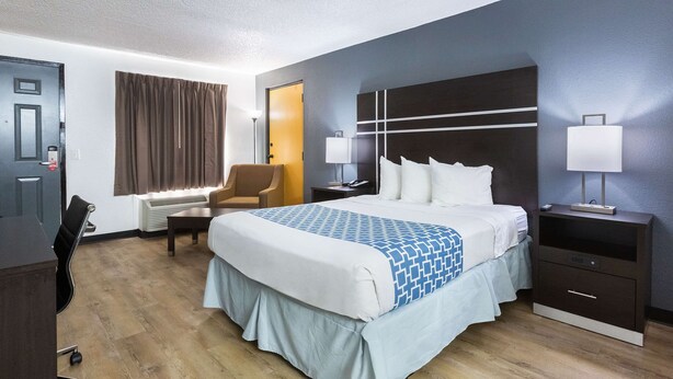 A hotel room with a bed, bedside tables, a desk, and a chair. - Econo Lodge Lithonia - Atlanta East (Lithonia)