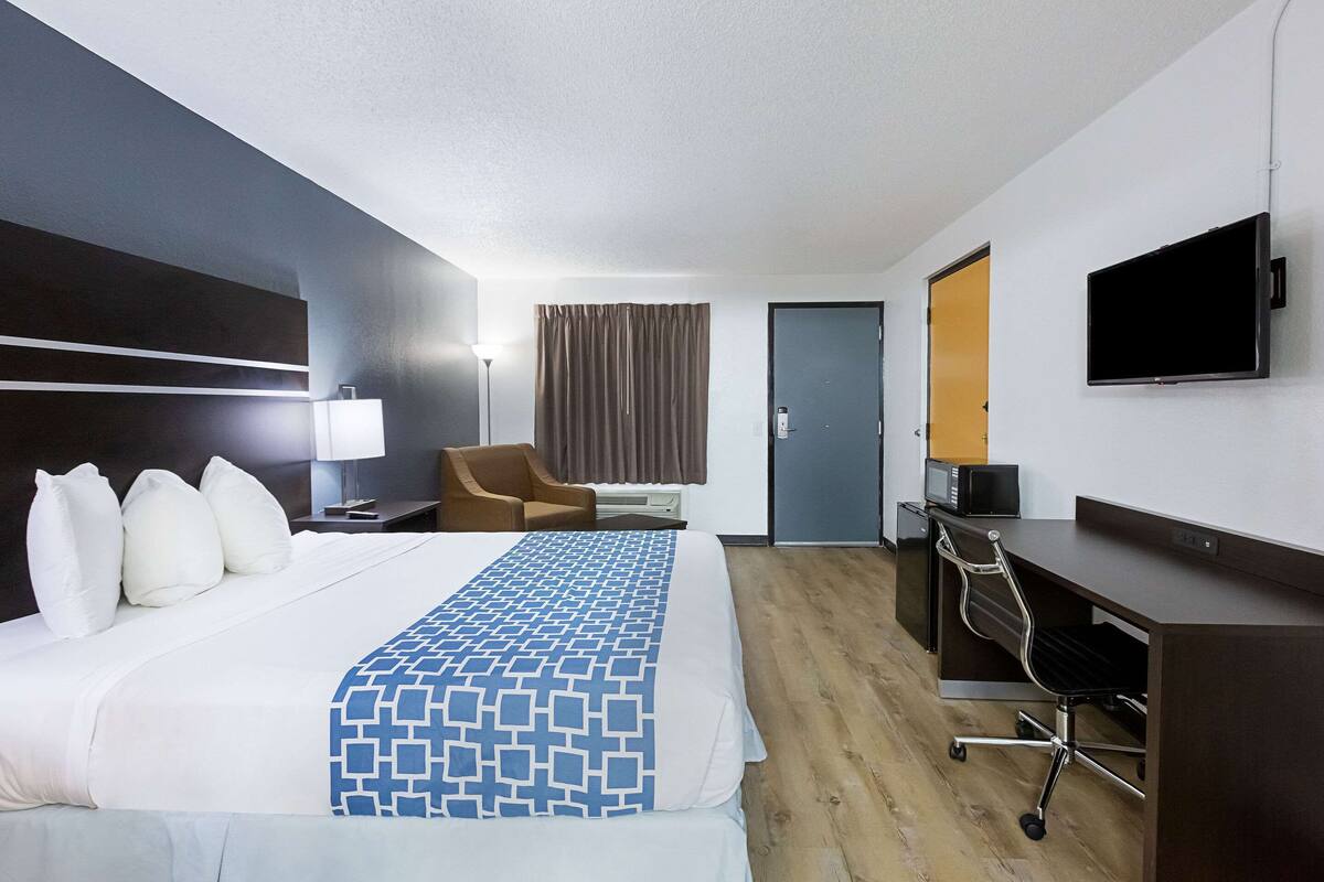 Ein Hotelzimmer mit Bett, Schreibtisch, Stuhl, Fernseher und Tür.