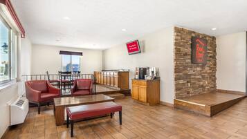 A hotel lobby with a seating area, a kitchen area, and a stone accent wall.