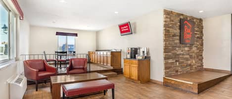 Un hall de hotel con zona de estar, área de cocina y una pared decorativa de piedra.