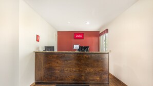 A reception desk with a wooden finish, a red wall, and a sign indicating free Wi-Fi in all rooms. - Red Roof Inn Paducah (Paducah)