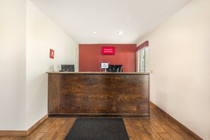 Uma receção com acabamento em madeira, uma parede vermelha e um aviso a indicar acesso gratuito à internet sem fios em todos os quartos.