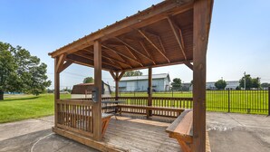 A wooden gazebo with benches and a table, surrounded by a concrete walkway and a green field. - Red Roof Inn Paducah (Paducah)