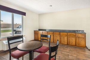 Cocina compacta con armarios de madera, encimera de granito y ventana con vista a un estacionamiento.