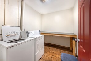 A compact laundry room with a washing machine, a drying rack, and a wooden bench. - Red Roof Inn Paducah (Paducah)