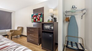 A hotel room with a bed, a desk with a computer, a refrigerator, a microwave, a lamp, and a wall-mounted ironing board. - Red Roof Inn Paducah (Paducah)