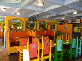 Un restaurante con mesas tipo cabina de colores y un tablero de menú.