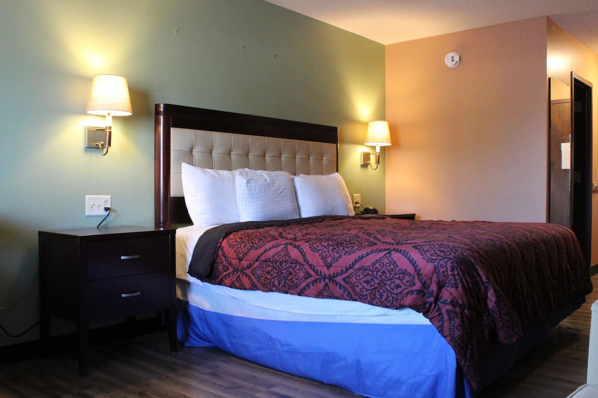 A hotel room with a large bed, two bedside tables, and two wall-mounted lamps.