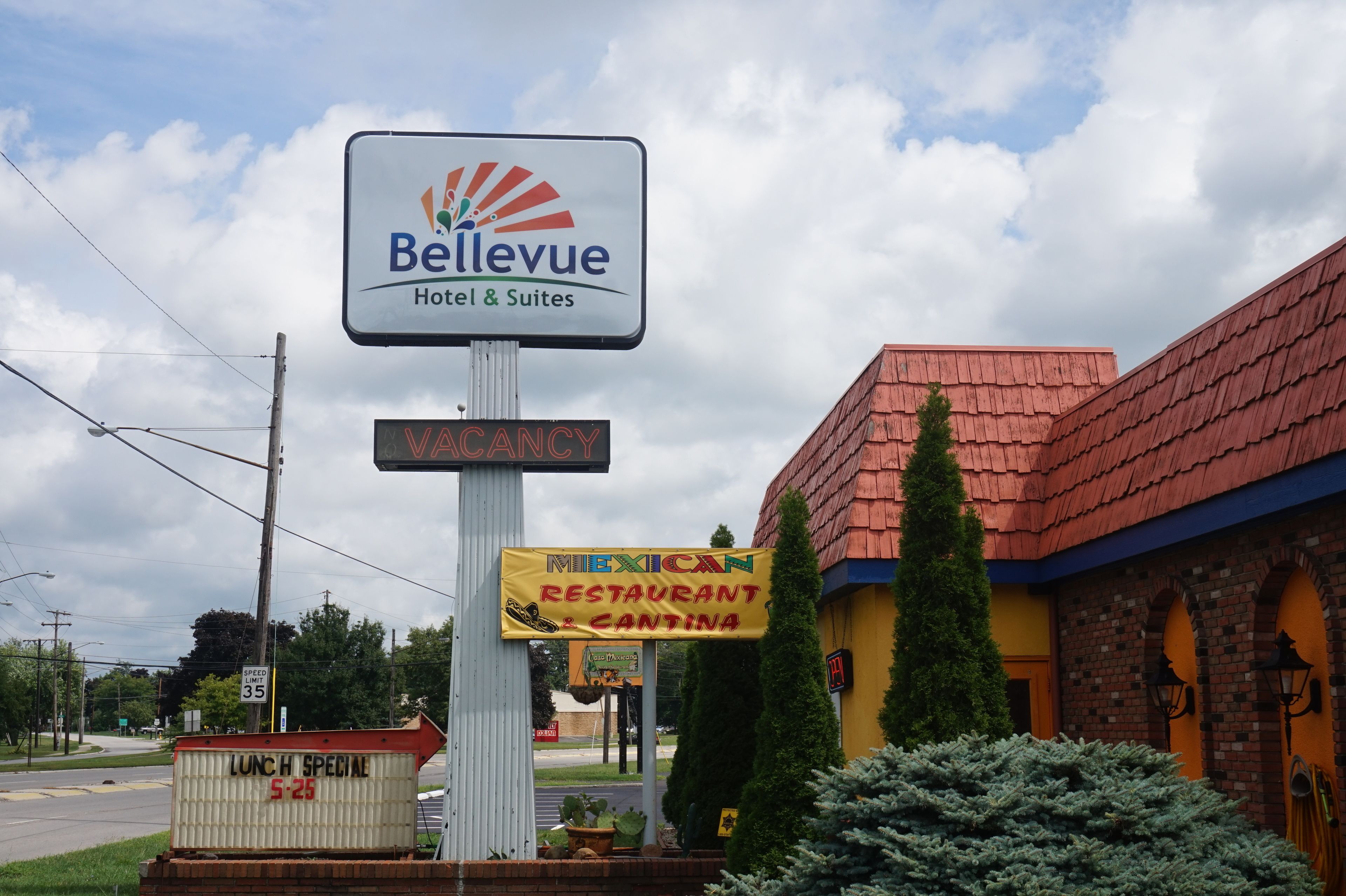 Señalización de hotel Bellevue Hotel & Suites, con un letrero que indica 'VACANCY', un letrero de 'RESTAURANTE MEXICANO' y un letrero de 'ESPECIAL DE ALMUERZO'.