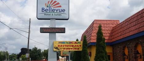 Señalización de hotel Bellevue Hotel & Suites, con un letrero que indica 'VACANCY', un letrero de 'RESTAURANTE MEXICANO' y un letrero de 'ESPECIAL DE ALMUERZO'.