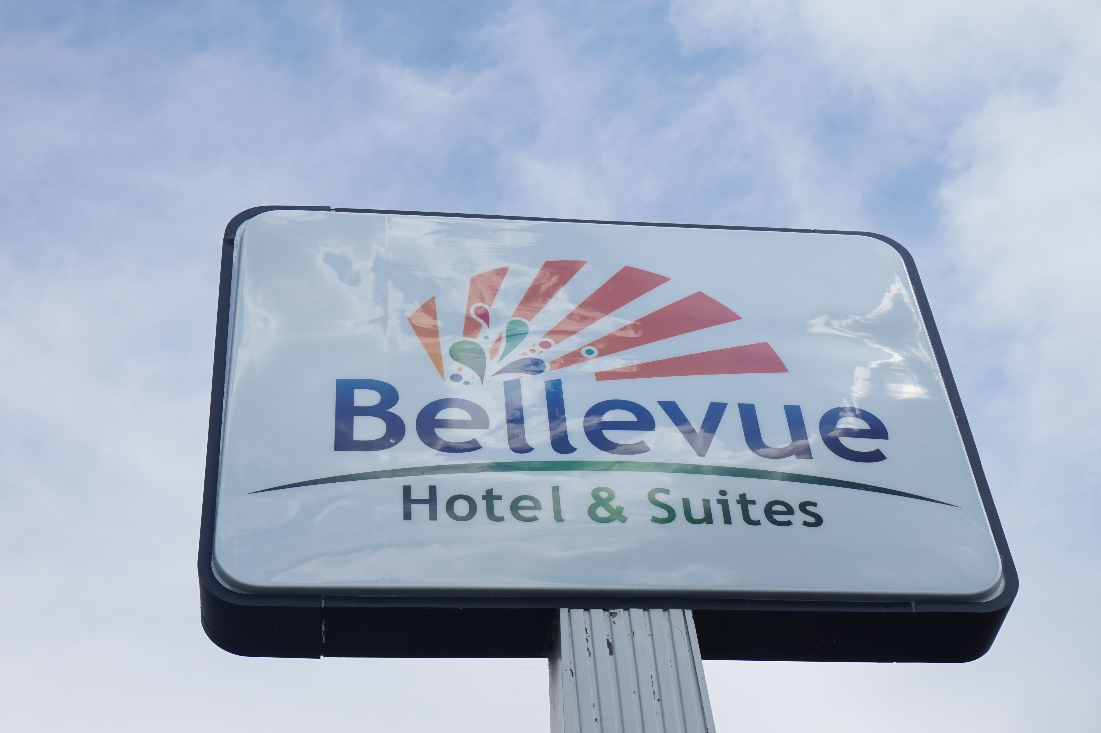 A sign for Bellevue Hotel & Suites with a logo featuring a stylized fan design.