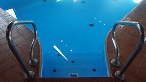Ein Schwimmbecken mit Metallgeländern und blau gefliestem Boden.