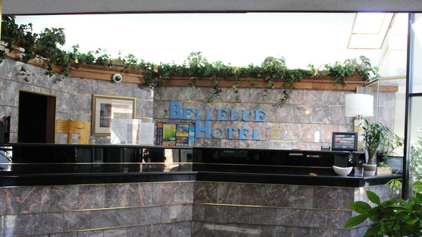 Ein Empfangstresen mit Marmorwand und einem Schild mit der Aufschrift 'Bellevue Hotel'.