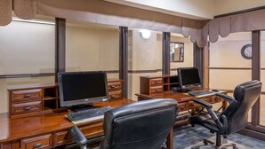 Een hotelkantoor met twee bureaus, elk met een computer, een stoel en een klein kastje.
